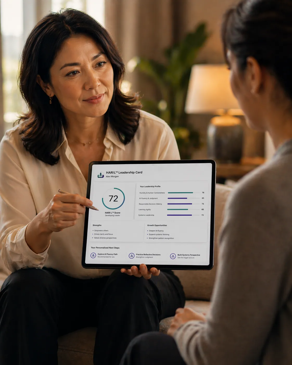 A coach reviewing a HARI L Leadership Card with a leader on a tablet
